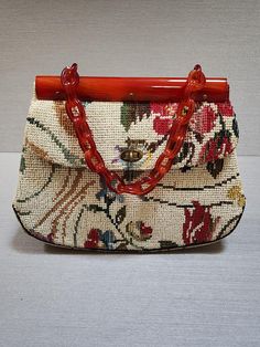 This vintage 1960's KADIN hand carry bag has a unique Lucite frame and Lucite links chain handle.  The floral tapestry has a neutral off white background with a beautiful floral pattern containing shades of reds/pinks, blues, greens, golds, browns, and a touch of lavender.  It is perfect for any occasion and season and is in mint/like new condition.  At the widest point it measures 12" and  9" at the narrowest across the top, and 3" deep.  It includes  protective feet, a turn lock closure and a long inside slit pocket and an inside zipper compartment. This is truly a statement bag to add to your handbag collection. Luxury Vintage Embroidered Bag, Hand Carry Bag, Ladies Bag, Handbag Collection, Statement Bag, Floral Tapestry, Carry Bag, Shades Of Red, Purses And Handbags