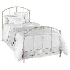 a metal bed with white sheets and pillows