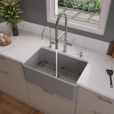 a white kitchen sink sitting under a window next to a counter top with utensils