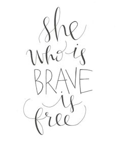 the words she who is brave is free are drawn in black ink on white paper