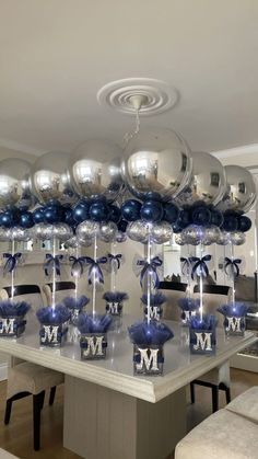 a room filled with lots of shiny silver balloons and blue bows on top of them