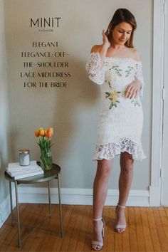 a woman standing in front of a wall wearing a white dress