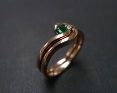 a gold ring with a green stone in the center on a black surface, close up