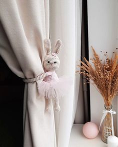 a stuffed animal is sitting on the window sill next to a vase with flowers