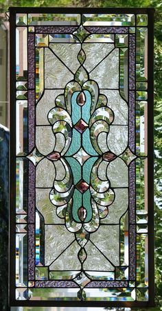 a stained glass window hanging from the side of a building with trees in the background