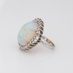 Stylish vintage natural opal ring (circa 1970s to 1980s) crafted in 14 karat white gold.   Natural opal measures 22mm x 14.5mm (estimated at 22 carats). The opal is in very good condition and free of cracks or crisps. Round brilliant cut diamonds total an estimated 1.40 carats (estimated at H-I colour and VS2-SI1 clarity).   The opal is full of colour and fire (opals are difficult to photograph and the true colours of the opal does not show in the pictures). The colour matrix is vivid from merma Oval Opal Ring With Polished Finish, Fine Jewelry Oval Opal Ring With Polished Finish, Oval Opal Ring With Polished Finish In Fine Jewelry, Formal Hallmarked Oval Cabochon Opal Ring, Formal Opal Birthstone Ring, Formal Opal Ring With Polished Finish, Hallmarked Oval Opal Ring, White Gold Cabochon Opal Ring, Oval White Gold Opal Cabochon Ring