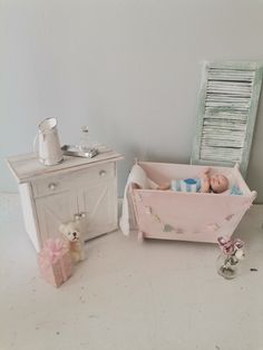 a baby in a pink crib next to a teddy bear and an old dresser