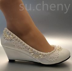 a woman's white high heeled shoes with pearls