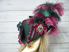 "Inspired by Marie Antoinette and Bridgerton, this is a beautiful dark green woolen pirate hat with burgundy satin pleated trim with dark green braid, dark green satin bows, burgundy satin cocarde with a jewel center, green and burgundy ostrich feathers. Sooo pretty! This is not an oversized pirate hat the upturn brim is about 4\". Please measure your head, this hat is 22.5\" for the inside circumference with a built-in hat sizer string. I cannot make the circumference bigger so please keep that in mind. All sales are final. Check out my other pirate hats. I ship Priority mail. I ship many times a week. If you need your item quicker let me know your zip code and I can figure shipping rates for you. Please let me know if you have any questions.   All sales are FINAL, no returns or exchanges Curved Brim Costume Hats And Headpieces For Fall, Fitted Hat For Fall Costume Party, Curved Brim Costume Hats For Fall, Fitted Hats For Costume At Carnival, Fitted Hat For Carnival Costume, Fitted Hat For Costume And Carnival, Fall Costume Hats And Headpieces With Curved Brim, Victorian Brimmed Costume Hats And Headpieces, Victorian Brimmed Costume Hat