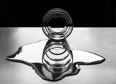 a glass vase sitting on top of a metal table next to a black and white background