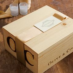 a wooden box sitting on top of a table next to two candles and some paper