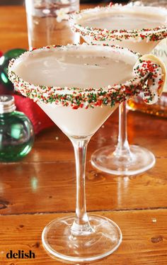 two martinis with sprinkles sit on a table next to christmas decorations