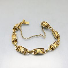 This handsome bracelet is as stylish today as it was in the 1960s. It has 7 rectangular links . The metal is goldplated with a floral design done in the traditional matte black enamel and gold plated metal damascene style .  The bracelet is in MINT condition.  It has a box insert type clasp, an attached safety chain and no markings.  The bracelet measures 7 1/2 inches long.  This would look divine layered with other gold bracelets.  It will arrive in a lovely gift box.   If you like vintage cost Gold Bracelet With Black Enamel, Antique Gold Rectangular Bracelet, Gold Art Deco Jewelry With Black Enamel, Antique Gold Enamel Bracelets, Vintage Gold Bracelets With Rectangular Links, Art Deco Gold Engraved Bracelet, Art Deco Engraved Gold Bracelets, Vintage Black Enamel Rectangular Jewelry, Vintage Enamel Jewelry With Rectangular Shape