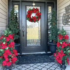 the front door is decorated for christmas with poinsettis and holly wreaths