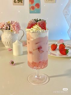 a dessert with strawberries and whipped cream in a tall glass on a white table