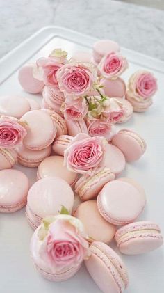 pink macaroons and roses on a white table with flowers in the middle for decoration