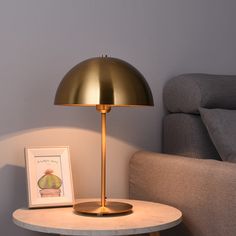 a table with a lamp on it next to a chair and a framed photograph in front of the light