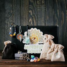 an assortment of jewelry sitting on top of a wooden table next to a black bag