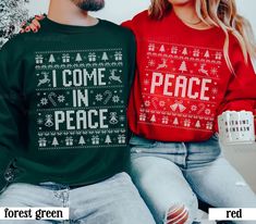 two people sitting next to each other wearing ugly sweaters that say i come in peace