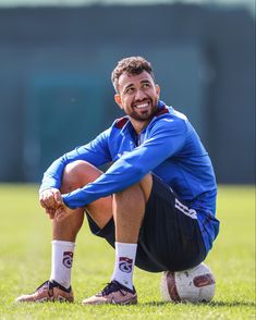 a man sitting on top of a soccer field wearing a blue shirt and black shorts