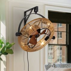 a fan mounted to the side of a wall next to a window with a plant in it