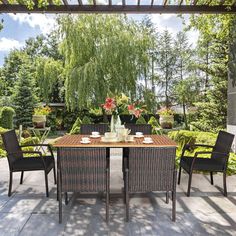 an outdoor dining table with four chairs and a vase full of flowers on the table