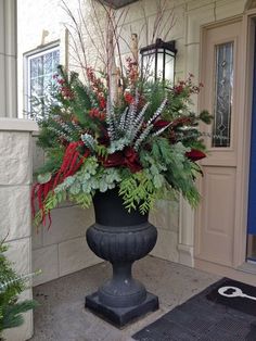 a planter filled with lots of green and red flowers sitting on top of a sidewalk