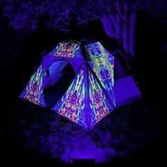 a lit up tent in the dark with trees and grass around it at night time