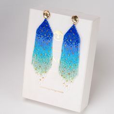 two pairs of blue and green beaded earrings in a white box with gold accents