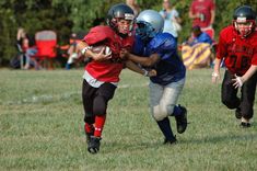 two young football players are running with the ball