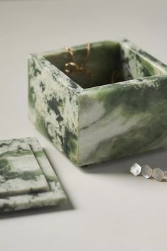 a green and white marble box sitting on top of a table next to a pair of earrings