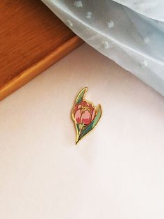 a small flower pin sitting on top of a table next to a piece of cloth