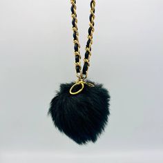 a black and gold chain with a fur ball hanging from it