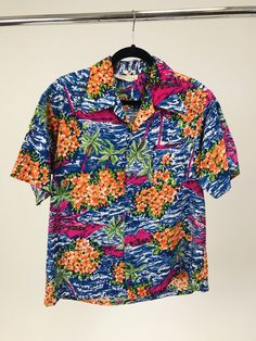 "Vintage 1940s-1950s Men's Cotton Hawaiian Shirt with Orange Hibiscus & Palm Trees | Resort Beach Wear | Made in Hawaii | Unisex This is a beautiful vintage Hawaiian printed button-up short-sleeve top from the 1940s or 50s. This Hawaiian shirt is full of bright, vibrant colors. The shirt shows orange hibiscus flowers as well as green and pink palm trees as well as pink volcanoes. All of which is surrounded by lush blue waves. The top has plastic buttons. Overall, this shirt is in near excell Affordable Vintage Multicolor Hawaiian Shirt, Orange Hibiscus, 1950s Mens, Resort Beach, Bohemian Chic Fashion, Vintage Clothing Online, Vintage Fits, Vintage Hawaiian, Hawaiian Print