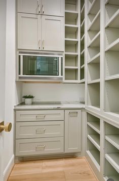 an empty kitchen with white cabinets and wood flooring is pictured in this image, there are no people or objects on the shelves