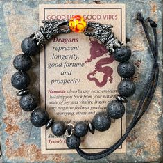 "Introducing the GOOD LIFE/GOOD VIBES bracelet! A bracelet that is beautiful and meaningful.    SYMBOLIC MEANING OF THIS BRACELET: 🔥 Dragon are symbols of protection, loyalty and trusting your instincts.   The positive energy from this bracelet helps you LIVE YOUR BEST LIFE! This POWERFUL bracelet:   👍 Features black dragon head beads, with matching hematite spacer beads, 👍 Is a 🔥 FIRE DRAGON (red & yellow central bead)  👍 Has 10mm BLACK LAVA beads,   👍 Is made with durable memory wire so Dragon Description, Lava Dragon, Black Dragons, Handstamped Bracelet, Dragon Bracelet, Viking Bracelet, Beautiful Dragon, Bracelet Box, Stamped Bracelet