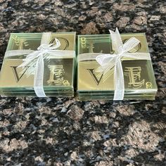 two square glass coasters with white ribbons tied around them on a granite countertop