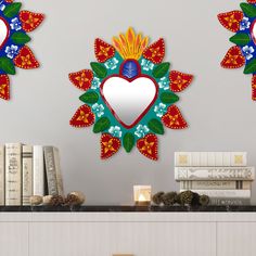 two decorative wall mirrors on top of a table next to books and candles in front of them