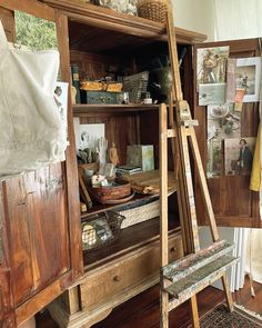 an artist's easel in front of a wooden cabinet with pictures on it