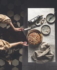 two people sitting at a table with some food on the table and one person reaching for something