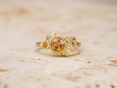 a close up of a gold ring with an orange and white diamond in the middle