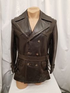 Amazing Rare Vintage 1950's Field & Stream Vented Brown Leather Trench Coat Jacket w Plaid Wool Lining Rancher Biker.  Coat has a 3  button front closure, a notched collar, a back vent,  a matching belt, 2 large front pockets, stitching details, and a removeable plaid wool warm lining.  See the super cool buckle details on the sleeve cuffs and the front pockets!  Coat is in amazingly Excellent condition.  See pics! Coat Measurements when buttoned:  Shoulder to shoulder 19, neck to bottom hem 31, Designer Fitted Leather Jacket With Belt Loops, Fitted Classic Vintage Brown Biker Jacket, Classic Fitted Vintage Brown Biker Jacket, Designer Fitted Outerwear With Belt Loops, Retro Brown Double-breasted Outerwear, Vintage Leather Jacket With Lapel Collar For Winter, Vintage Double-breasted Leather Jacket For Fall, Vintage Double-breasted Outerwear, Vintage Long Sleeve Biker Jacket With Button Closure