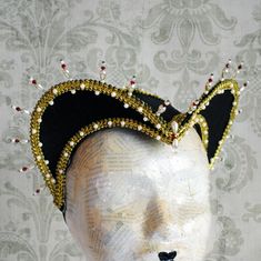 This royal Tudors inspired attifet headdress will make an excellent addition to your historical costume. It is covered with black silk shantung and embellished with golden braided trimming all around the edges.This unique piece wouldn't be complete without all those wonderful pearl bead details that add some royal flair to it's elegance. Choose between only pearl decoration or a combination of pearl beads and small red crystals to add just a pop of color. The headpiece is very light and comforta Elegant Tall Crown Headpieces For Costume Party, Fitted Costume Bonnet, Fitted High Crown Costume Hat For Carnival, Vintage Fitted Costume Hats And Headpieces For Carnival, Vintage Fitted Costume Hats For Carnival, Fitted High Crown Hat For Carnival, Handmade Fitted High Crown Mini Hats, Handmade Fitted Mini Hat With High Crown, Elegant High Crown Headpiece For Costume