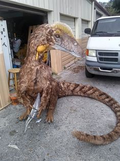 a fake bird sitting on the ground next to a white van in front of a garage