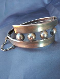 Taxco Sterling silver (stamped, tested) Amazing patina Balls on center piece Cuff style Hinged Push button clasp with safety chain Modernist statement piece Materials: sterling silver Measurements: Width, band - .25inches (.63cm) Width, design piece - 7/8 inches (2.22cm) Total length - 7inches (17.78cm) Size of opening - 2.25 x 2.25inches (5.71 x 5.71cm) Provenance: 1950-early1950s Stamp: Eagle stamp MCS Hecho en Mexico 20201219J953 Condition: Very good vintage with minimal, normal wear. Good pa Vintage Cuff Bangle With Polished Finish, Vintage Cuff Bracelet With 17 Jewels For Formal Occasions, Vintage Polished Cuff Jewelry, Vintage Hallmarked Cuff Bracelet For Formal Occasions, Vintage Formal Jewelry With Oyster Bracelet, Modernist Metal Bangle For Formal Occasions, Formal Vintage Hallmarked Cuff Bracelet, Formal Modernist Metal Bangle, Vintage Round Cuff Bracelet Collectible