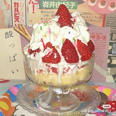 an ice cream sundae with strawberries and whipped cream in a glass dish on a plate