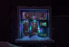 a window covered in snow with christmas lights