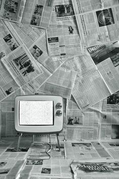 an old tv sitting on top of a table covered in newspaper sheets and newspapers flying around it