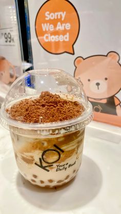 a plastic cup filled with food on top of a counter next to a sign that says sorry we are closed