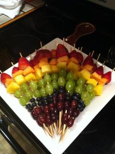 a platter filled with fruits and skewers on top of a stovetop